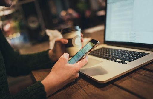 Электроника: человек пишет на ноутбуке с телефоном и чашкой для кофе.